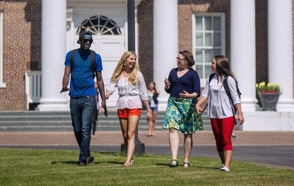 4 people walking on the lawn in front of Davidson Hall at Coker University